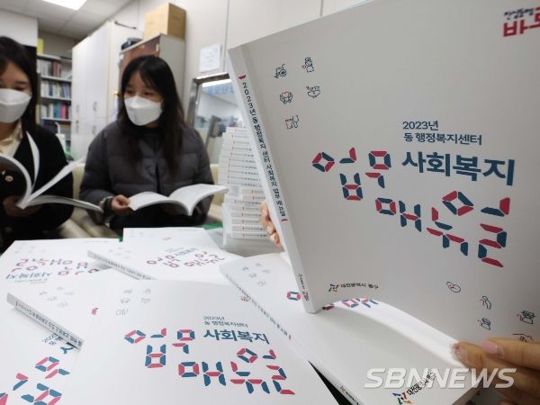 동구청 생활보장과 직원들이 배부 예정인 2023년 동 행정복지센터 사회복지 업무 매뉴얼을 살펴 보고 있다.